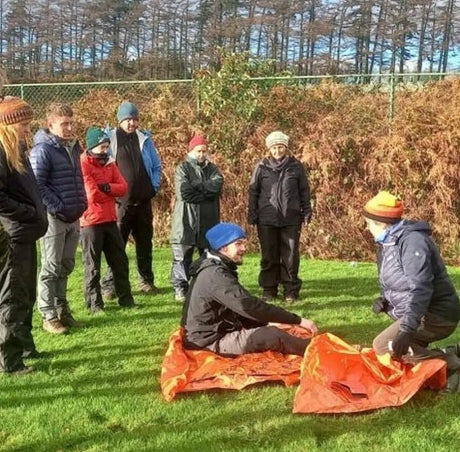 Group of people outdoors with one person sitting on a blanket