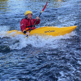 Person kayaking in a yellow kayak with 'Spade' branding on a river.