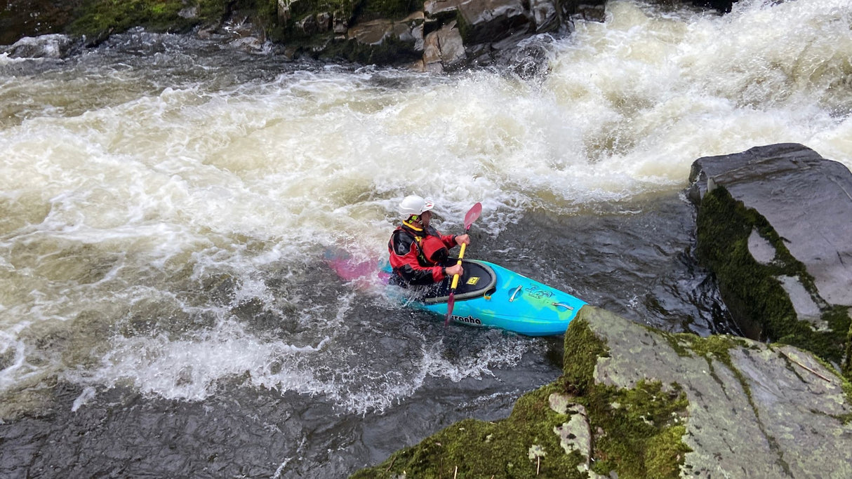 Person kayaking in a river with rapids and rocks